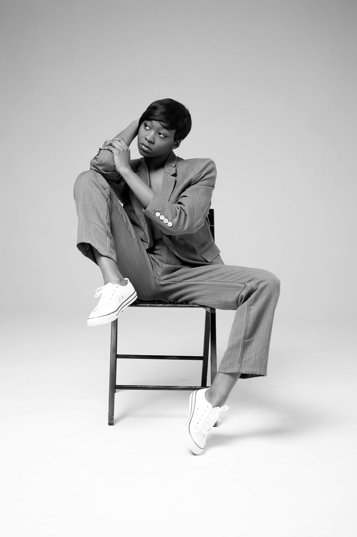 Woman Wearing Suit Jacket and Pants Sitting on Black Steel Chair